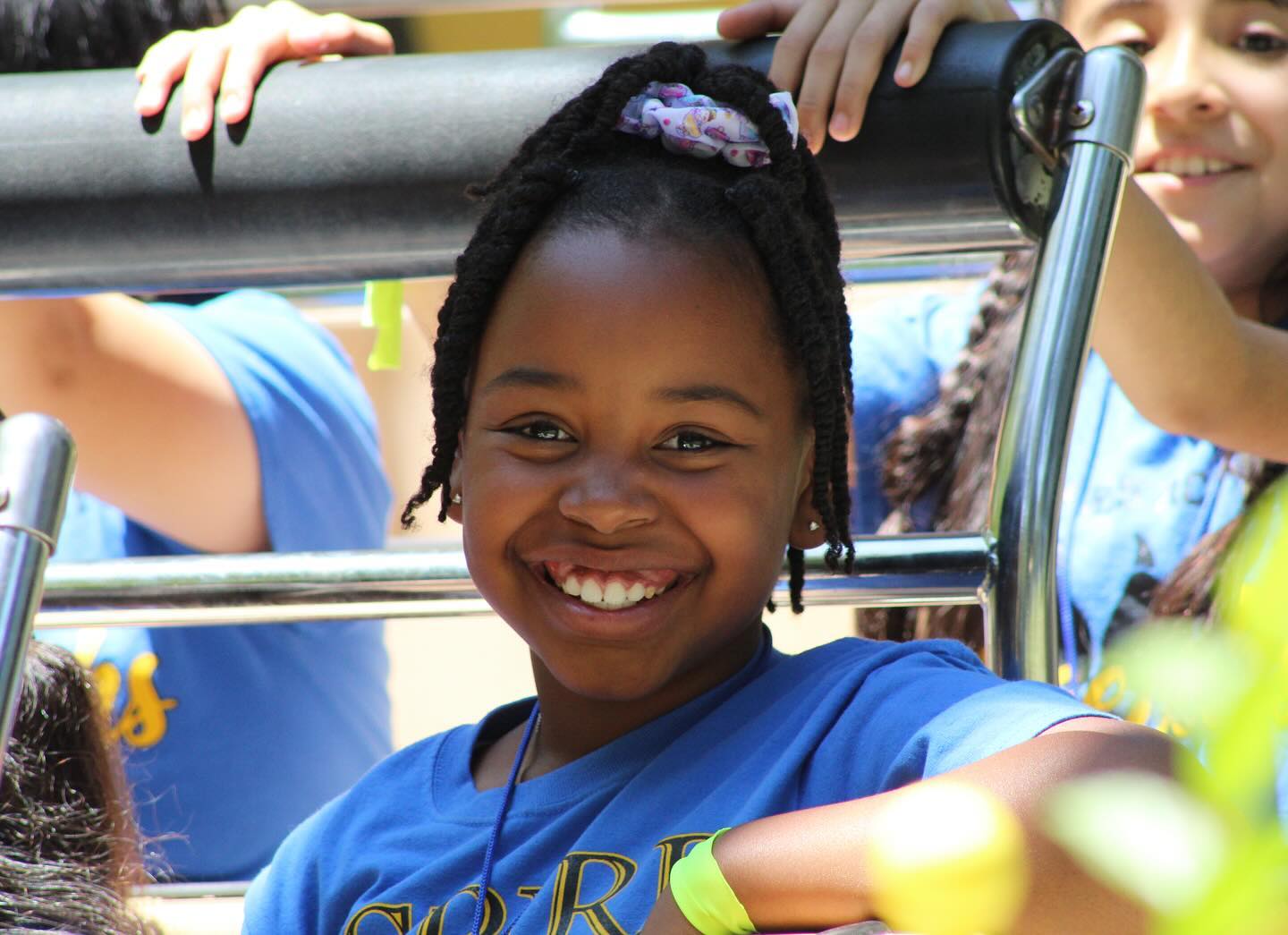 School girl wearing a blue school shirt sitting in the Banana Split ride smiling.